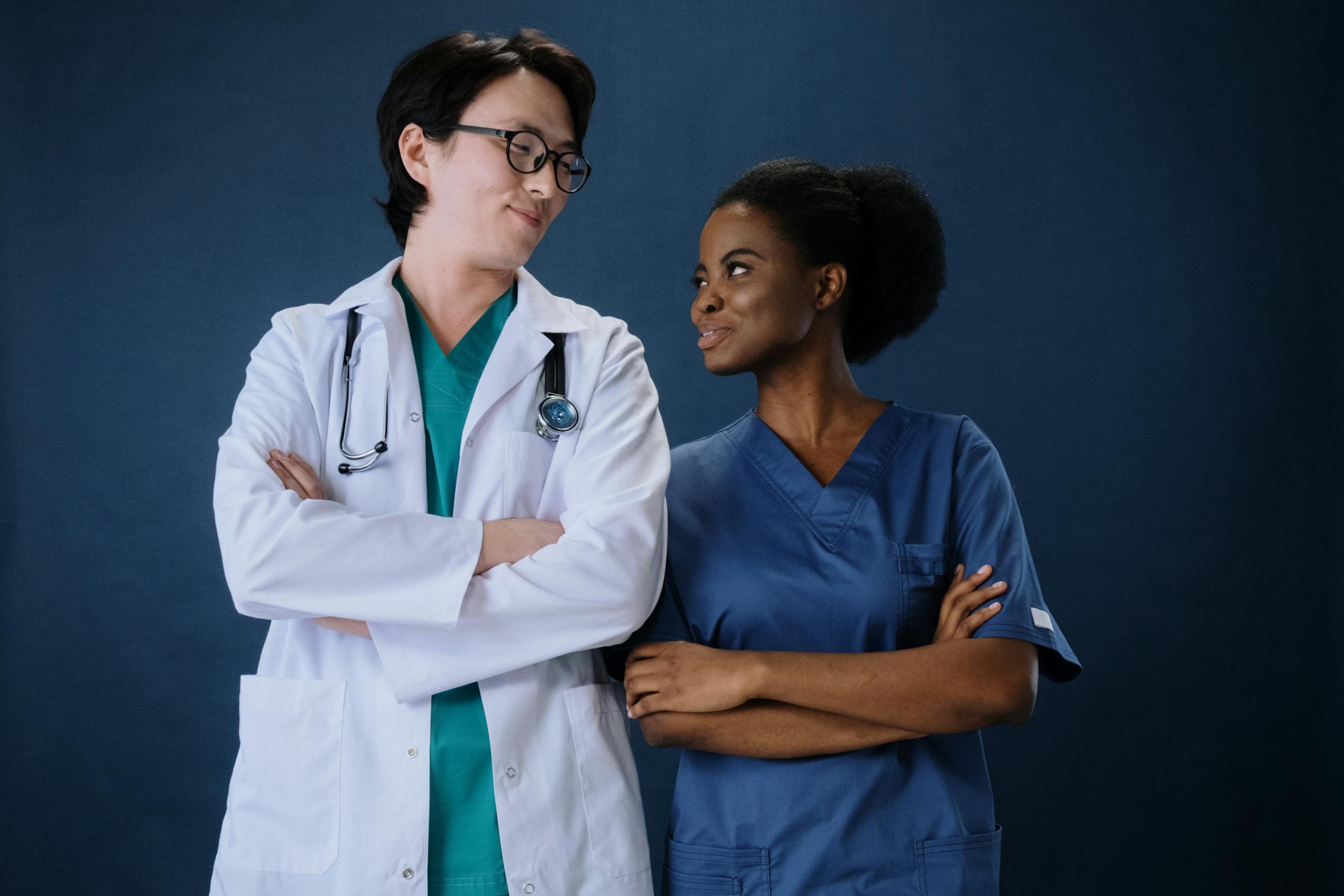 Woman in Blue Scrub Suit Standing Beside a Man in White Laboratory Gown